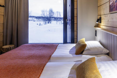 Schlafzimmer mit Blick auf die Winterlandschaft der Deluxe-Villen am Fluss 