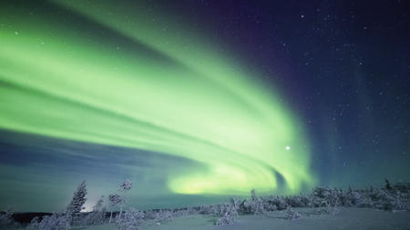 Die Polarlichter leuchten hell über der weißen Landschaft