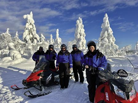 Motorschlittengruppe inmitten von märchenhafter Winterlandschaft in Lappland