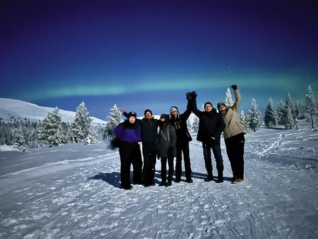 Glückliche Gäste vor dem Nordlicht beim Lapland Hotel Pallas